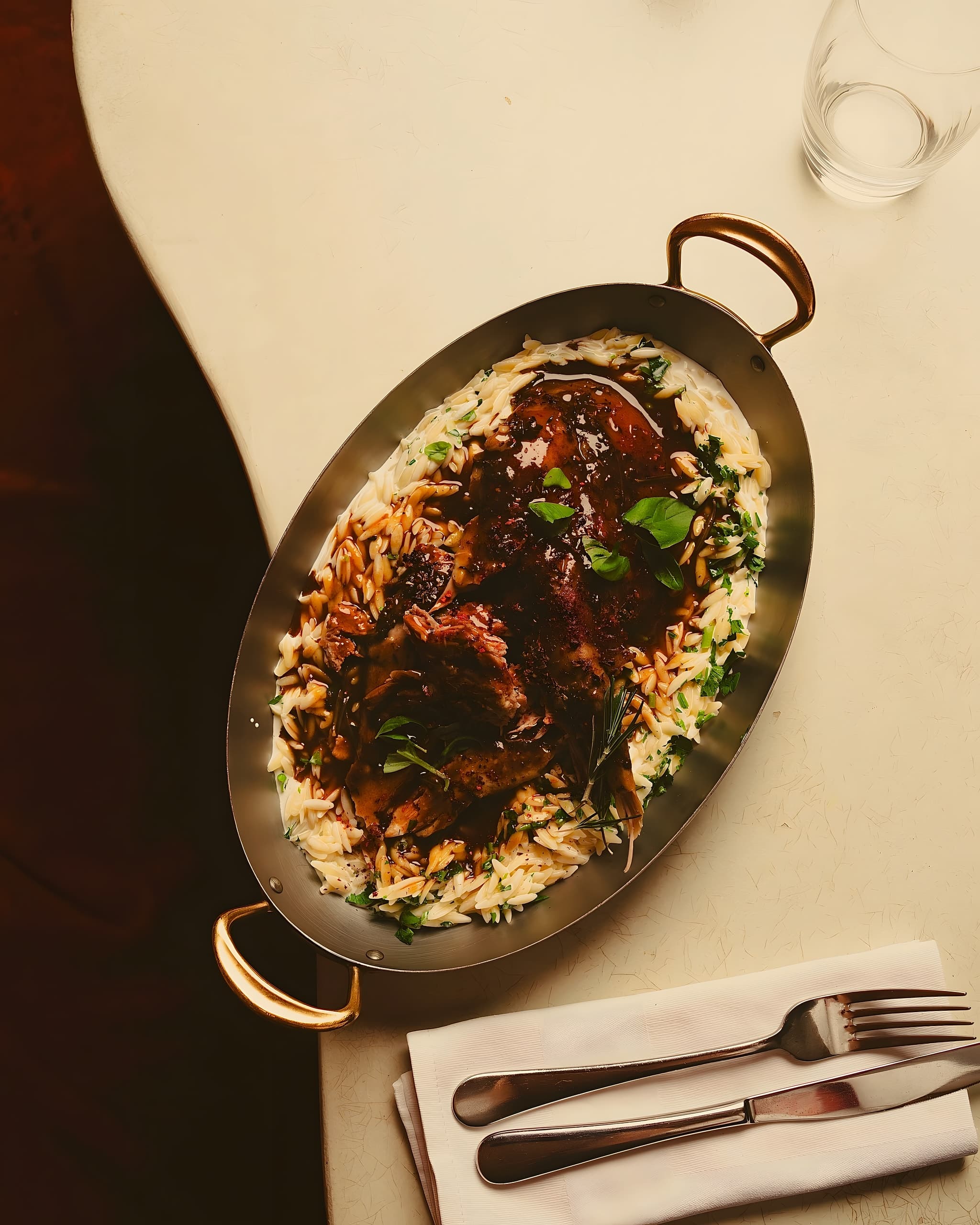 Agneau confit sur orzo, servi en plat de cuivre