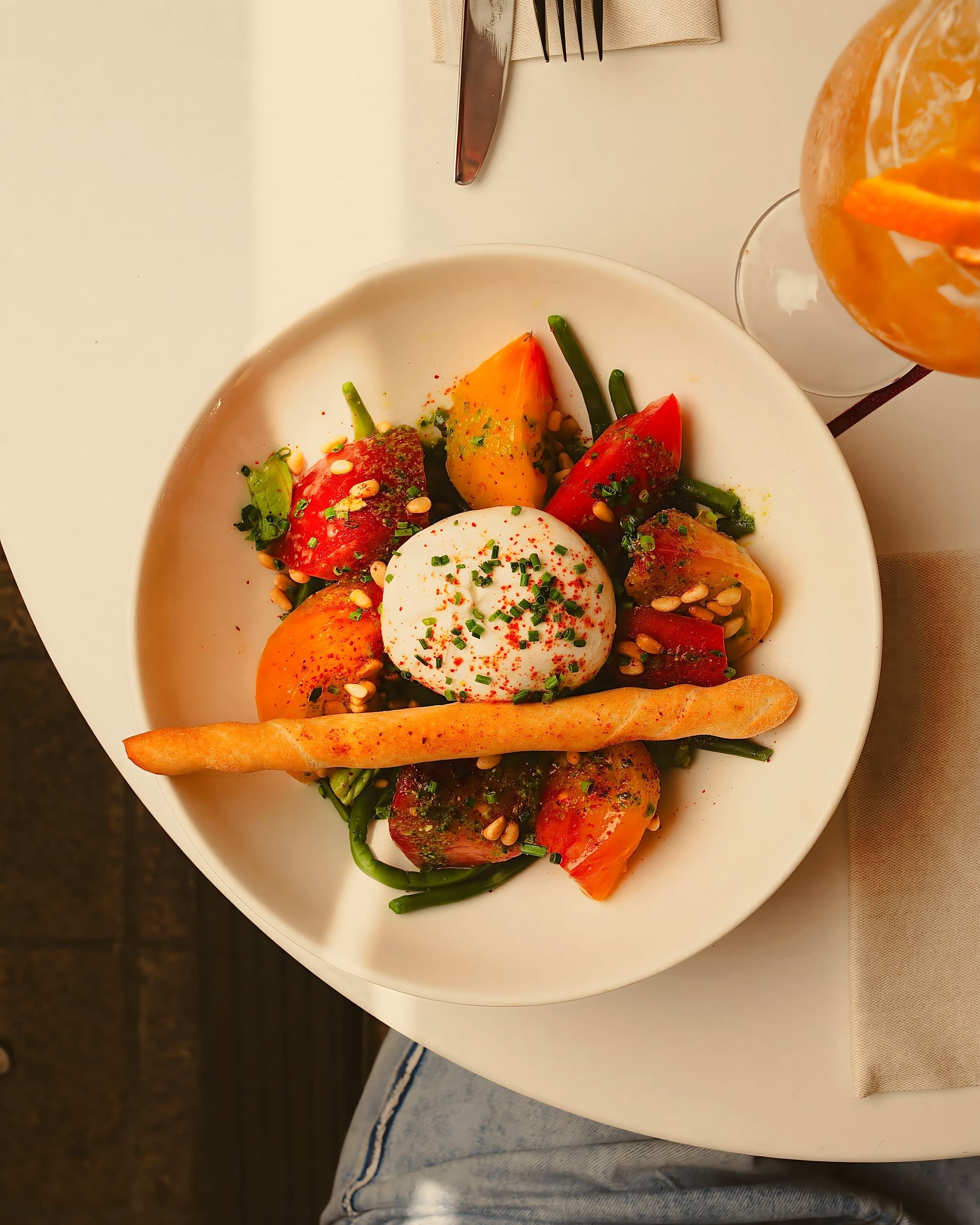 Burrata aux tomates anciennes et pignons dans une flaque de soleil